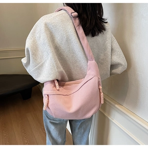 Pink corduroy crossbody bag worn over the shoulder by a model in a bright indoor setting