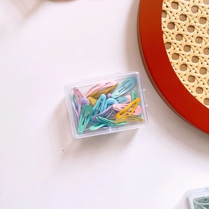 Detailed view of colorful candy-colored metal hair clips in a clear storage box