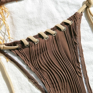 Detail of dark brown crinkled bikini bottom with beige drawstring and metallic eyelets