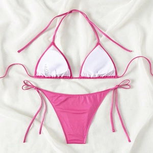Bright pink metallic string bikini set with halter top and side-tie bottoms on white fabric