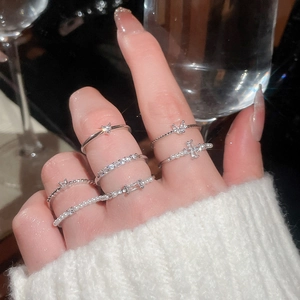 Detail of silver rings set with zircon and pearls layered on hand with cozy knitwear