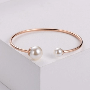 Minimalist rose gold open bangle featuring two elegant pearls on a geometric display