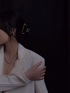 Close-up of pearl chain necklace and gold geometric hair clip on a model