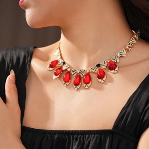 Detailed macro of vintage golden necklace with a red teardrop gem and sparkling crystals