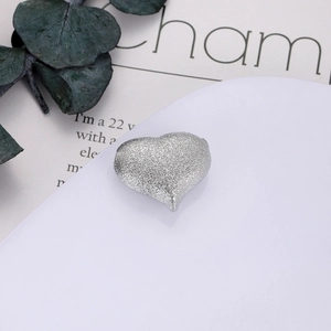 Dettaglio macro di un ciondolo a cuore argento con texture glitter per gioielli