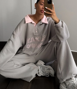 Détail du col contrasté rose avec trois boutons sur un sweat-shirt gris oversize