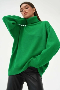 Gros plan détaillé d'un pull à col roulé vert émeraude avec une maille épaisse et coupe ample