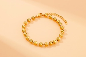 Detailed shot of golden bead bracelet featuring a secure lobster clasp and adjustable chain