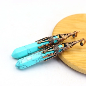 Macro shot of turquoise pendants with antique bronze caps on a minimalist wood base