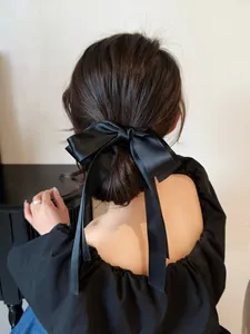 Détail d'une grande barrette à nœud en satin noir avec de longs rubans élégants