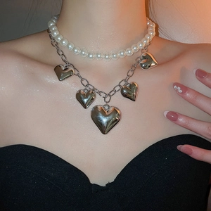 Close-up of double-layer beaded pearl necklace with silver heart charms on a model