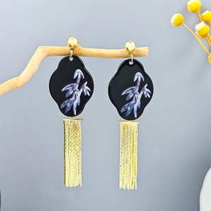 Detail of long gold metal tassels and vintage cloud pattern on traditional earrings