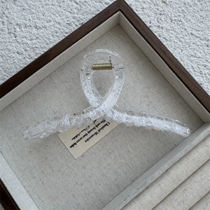 Close-up of a large transparent lace mesh hair claw clip with golden metal spring