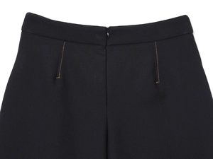 Détail de la fermeture éclair invisible et des surpiqûres orange sur le short noir