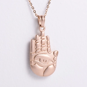 Macro shot of rose gold Hamsa hand pendant necklace with detailed eye embossing detail