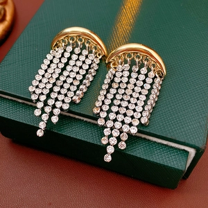 Detail of gold crescent stud earrings with silver rhinestone tassel chains on jewelry box