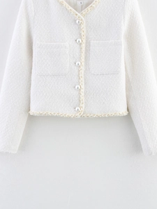 Détail d'une veste en tweed blanc avec boutons perlés élégants et liseré doré tissé