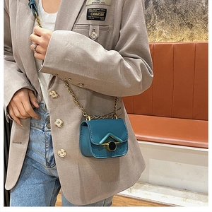 Dettaglio mini borsa a tracolla verde teal con fibbia a V dorata e catenella
