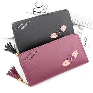 Detail of long zipped wallets with litchi texture leather, floral decor and tassel charm
