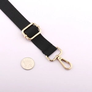 Detail view of adjustable black nylon strap with gold lobster clasps and sizing coin
