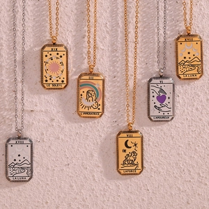 Detailed view of 18K gold and silver tarot card pendants on a textured rock wall