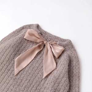 Pink knitted sweater featuring large satin ribbon bow and honeycomb knit texture detail