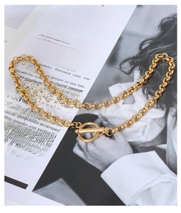 Artistic close-up of gold chain necklace with toggle clasp on a magazine background