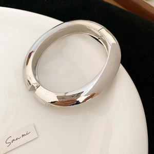 Gros plan détaillé d'un bracelet jonc argenté à charnière sur une assiette en céramique