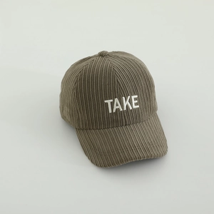 Détail de la texture en velours côtelé et broderie blanche TAKE sur la casquette