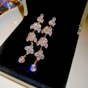 Close-up of golden leaf tassel earrings with sparkling marquise and teardrop crystals