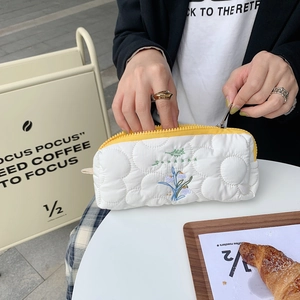 Gesteppte weiße Federtasche mit gelbem Reißverschluss und blauer Blumenstickerei für Schule