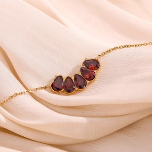 Detailed macro view of an 18K gold-plated bracelet with five red garnet-style gemstones