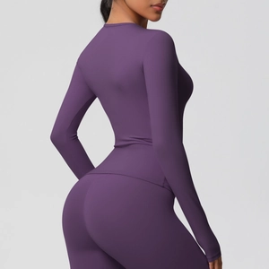 Vue latérale d'une femme en haut de sport violet à manches longues et legging assorti