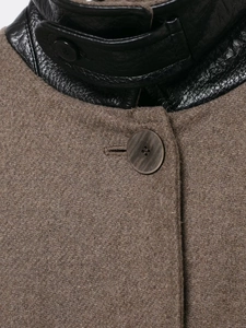 Dettaglio del collo alto con patchwork in lana marrone e pelle nera su cappotto lungo
