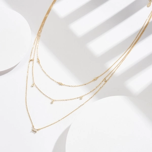 Detailed close-up of a three-layered gold S925 silver necklace with sparkling gemstones