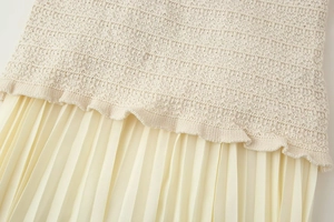 Détail de l'ourlet en maille crème cousu avec une jupe en mousseline plissée