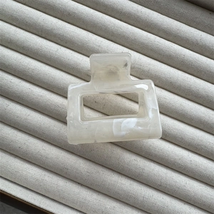 Close-up of square cream marble pattern hair claw clip with cutout on velvet display tray