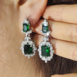 Elegant emerald green rectangular drop earrings with zircon crystals shown on ear