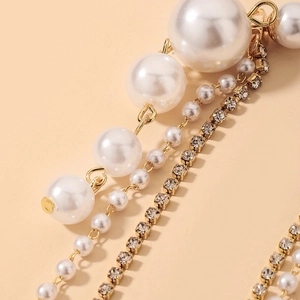 Macro detail of elegant gold-tone tassel earrings with multiple faux pearls and sparkling rhinestones