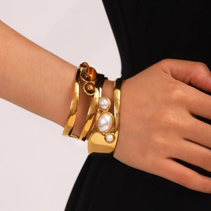 Detailed close-up of gold stainless steel cuff bracelets with tiger eye and pearl inlays