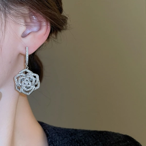 Close-up of elegant silver flower earrings with white zircon stones on a female ear