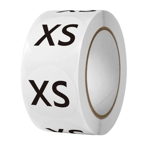 Close-up of a roll of 1-inch white circular size stickers with black XS label for clothing