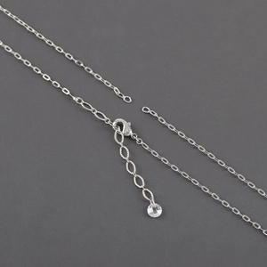 Macro detail of silver rhodium plated cross chain necklace with lobster clasp and bead