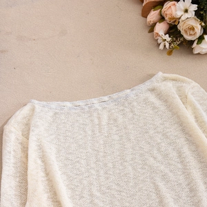 Gros plan sur la texture du tricot crème et les détails de l'encolure bateau