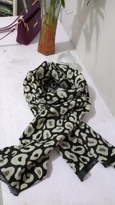 Close-up of leopard print scarf with tassels on white wooden table with home decor