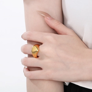 Gros plan d'une bague coeur dorée minimaliste avec texture de métal liquide sur le doigt
