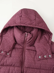 Détail d'une veste à capuche bordeaux avec texture matelassée et boutons métalliques