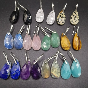 Array of multi-color faceted teardrop gemstone earrings on black textured surface