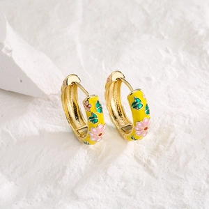 Gold plated hoop earrings with yellow enamel and pink flower pattern on stone background