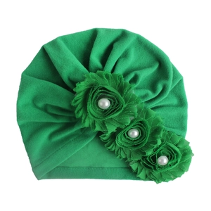 Detailansicht der grünen Baby-Turban-Mütze mit weichem Stoff und Perlenblumen-Deko